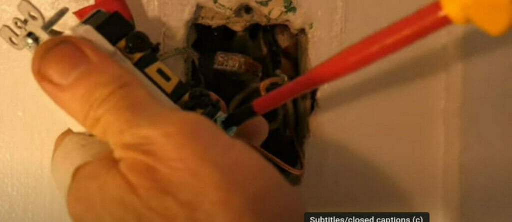 A person attaching the ground wire on the green screw 