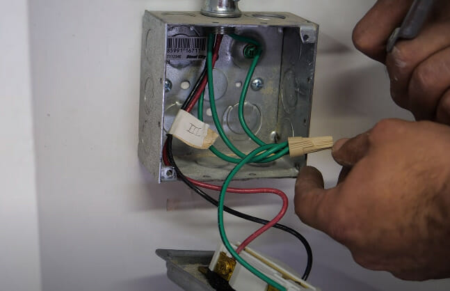 A person grounding an electrical box