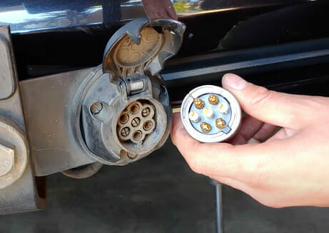 A person is putting a plug into the side of a car
