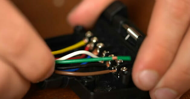 A person wiring a 7-pin trailer plug