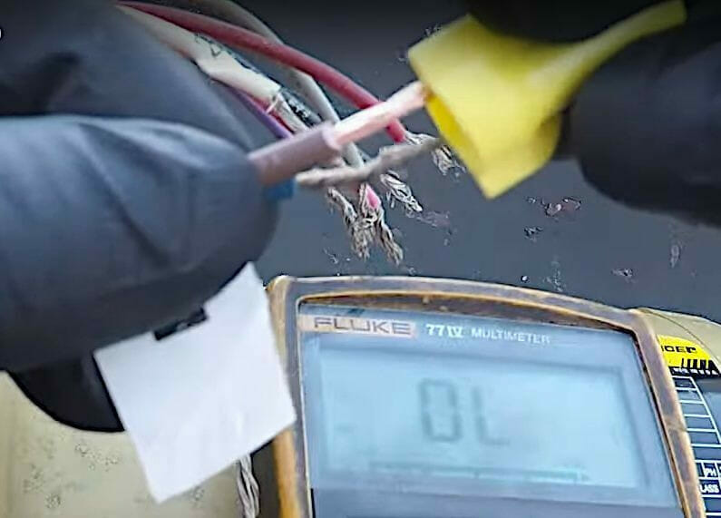 A person is using a meter to test a wire for a 3 phase motor.