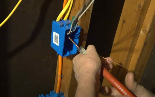 A person properly twisting wires in a blue box