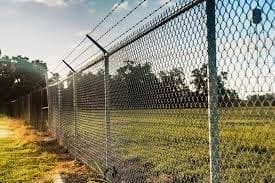 A chain link fence with a grassy field in the background