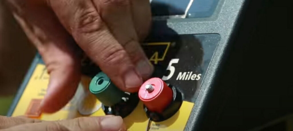 A person connecting the grounding post to the knob on the electrical box 