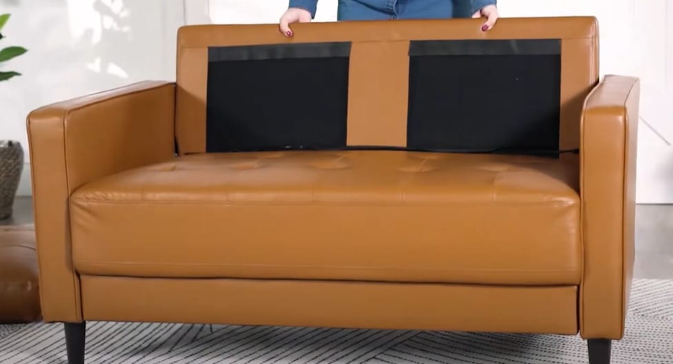 A person standing in a brown couch with vegan leather fabric