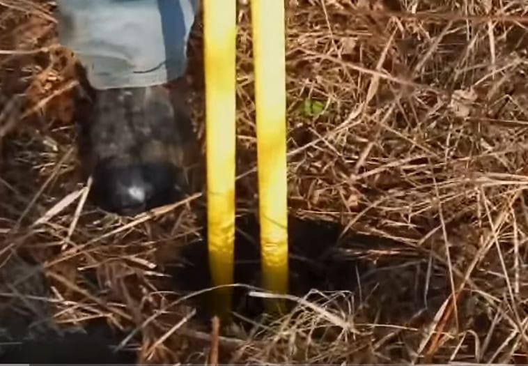 A person digging holes for the fence posts