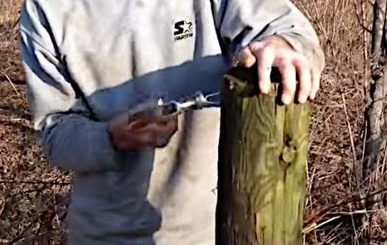 A man embed hooks into the fence post