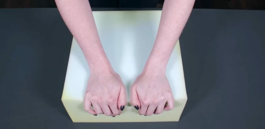 A woman's hand pressing on a block of foam