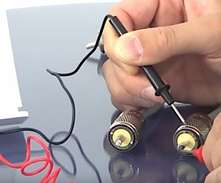 A person is using a multimeter to test the coax cable signal