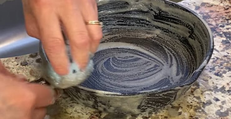A person brushing the pan with soap