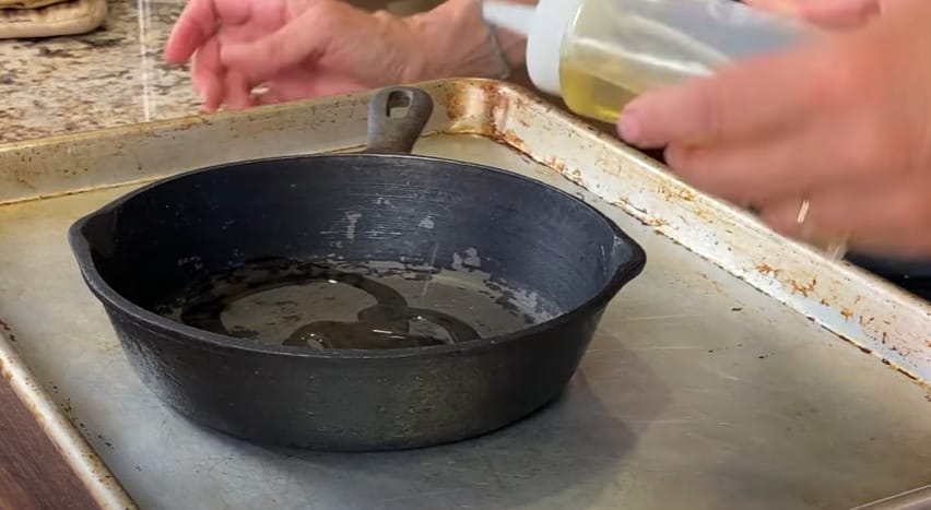 A person pouring oil at the pan