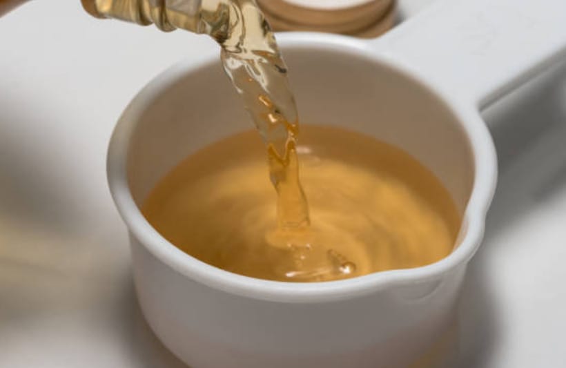 A person pouring a vinegar into a cup