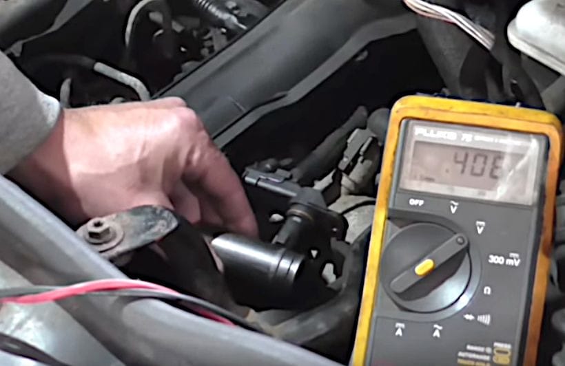A person testing the signal pin on the hall effect sensor