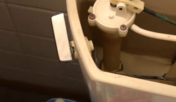 An open toilet tank and flush handle