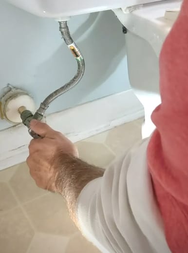 A person rechecking the connections and seals of a toilet