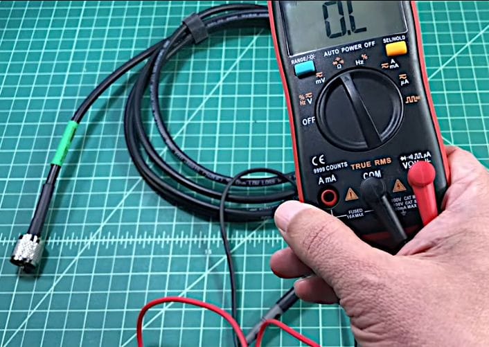 A person is setting the multimeter to measure ohms