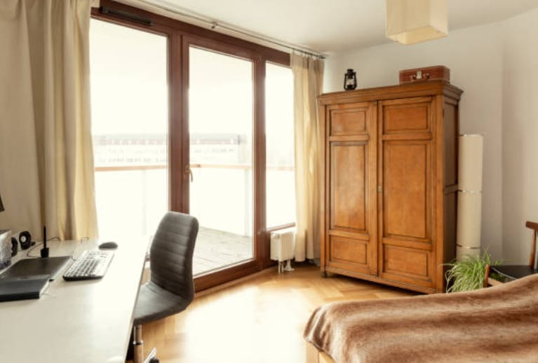 A bedroom with a bed, desk, chair, and closets