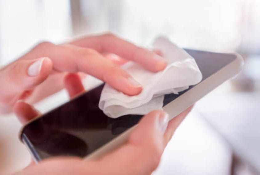 A woman cleaning her phone with a tissue