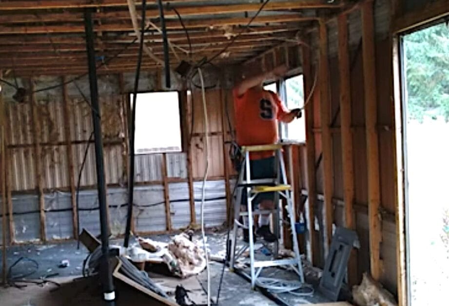 A man is working on running electrical wire in a house