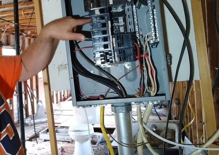 A man installing a circuit breaker box in a home
