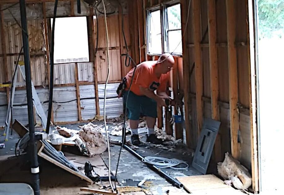 A man is working on a room that is being remodeled, specifically focusing on how to run electrical wire