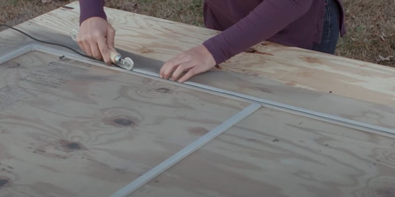 A person cutting a new screen for a window
