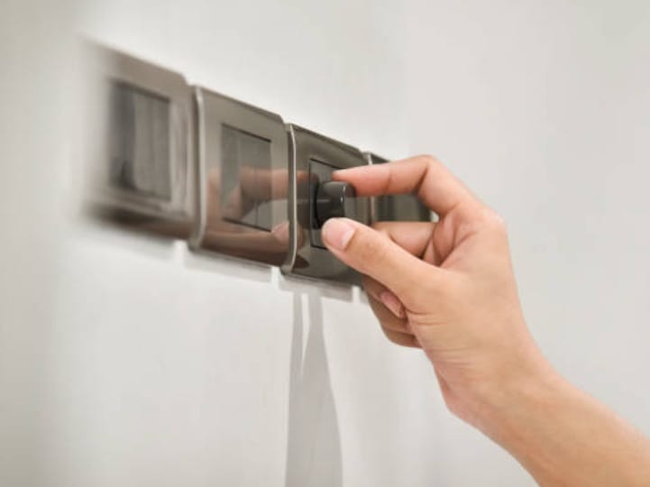 A hand is navigating a switch on a wall