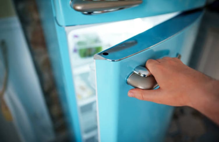 A person opening a blue green mini fridge