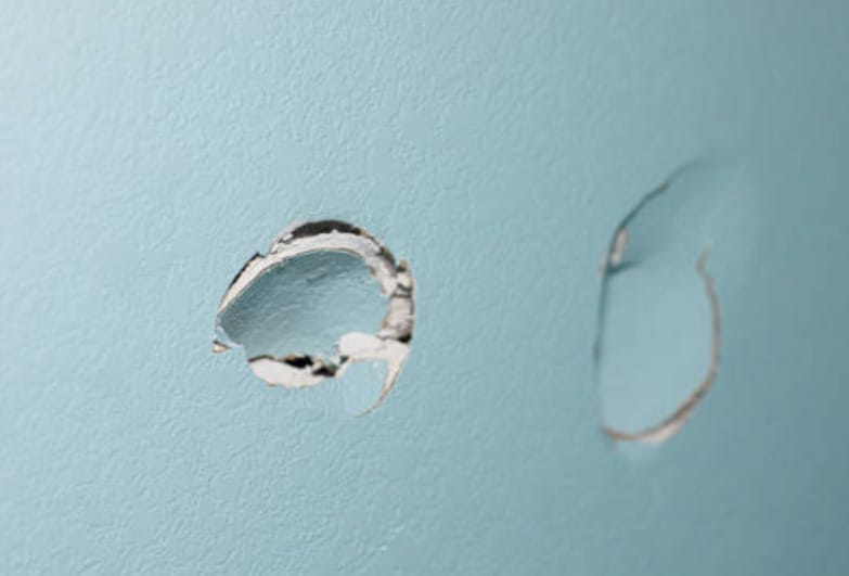 A close up look of a crack hole on the sage green wall