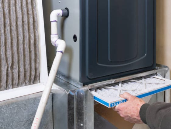 A man performing home repairs by cleaning the air filter of a furnace