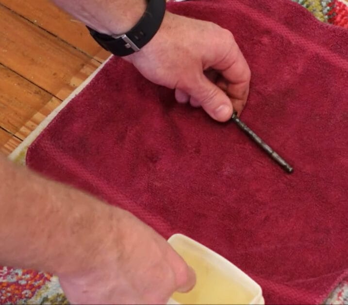 A person holding a hinge pin and laying it on a red clothe