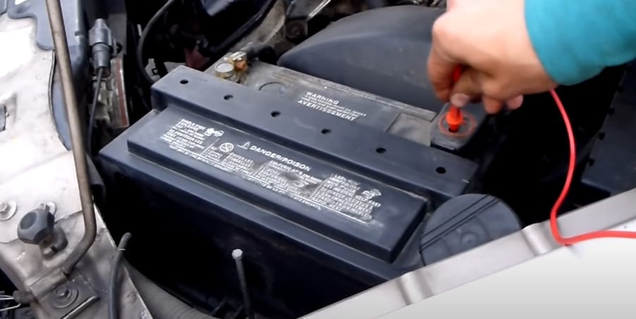 A person is using a multimeter to test a car battery