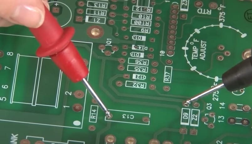 A person is using a multimeter on a circuit board