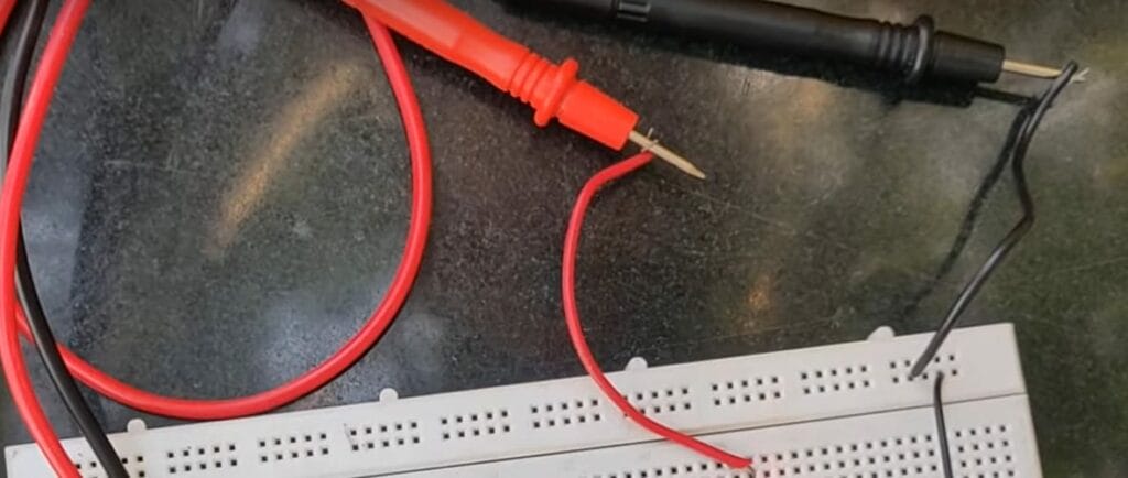 A circuit board with wires and a multimeter's probe