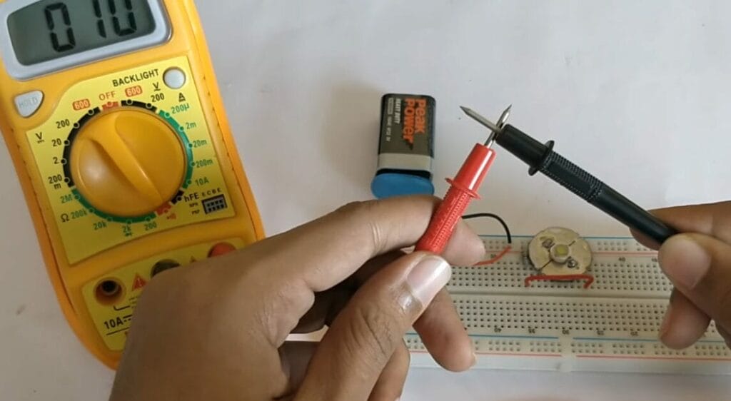 A person is holding a multimeter probe to test a circuit board
