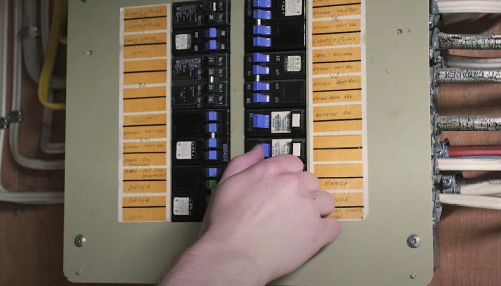 A person is switching off a circuit breaker in a main panel