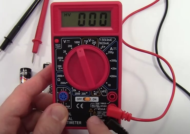 A person is using a Cen Tech multimeter to test a battery