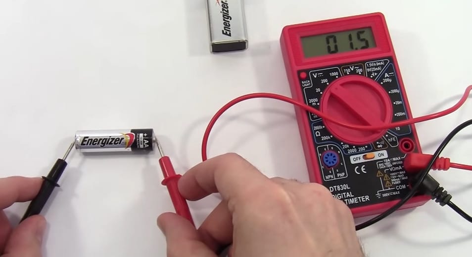 A person is using a Cen Tech multimeter to test a battery