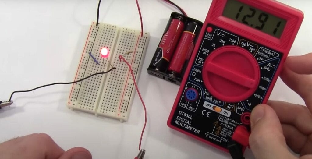 A person is using a Cen Tech multimeter to test a circuit and a double A batteries