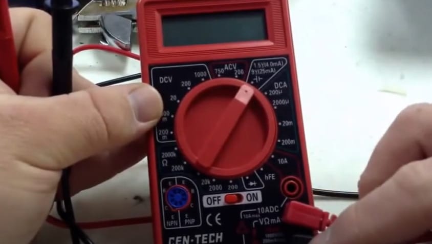 A person is using a Cen Tech multimeter to test a wire