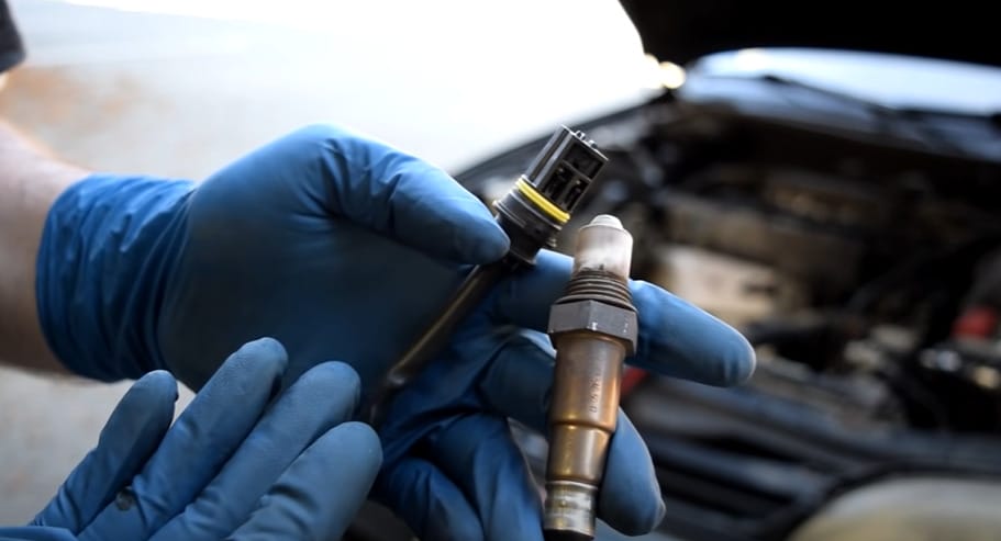 A person in blue gloves holding two 02 sensors