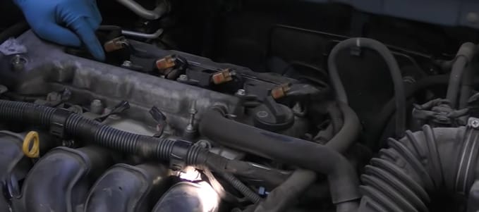 A man with blue gloves is working on the engine of a car