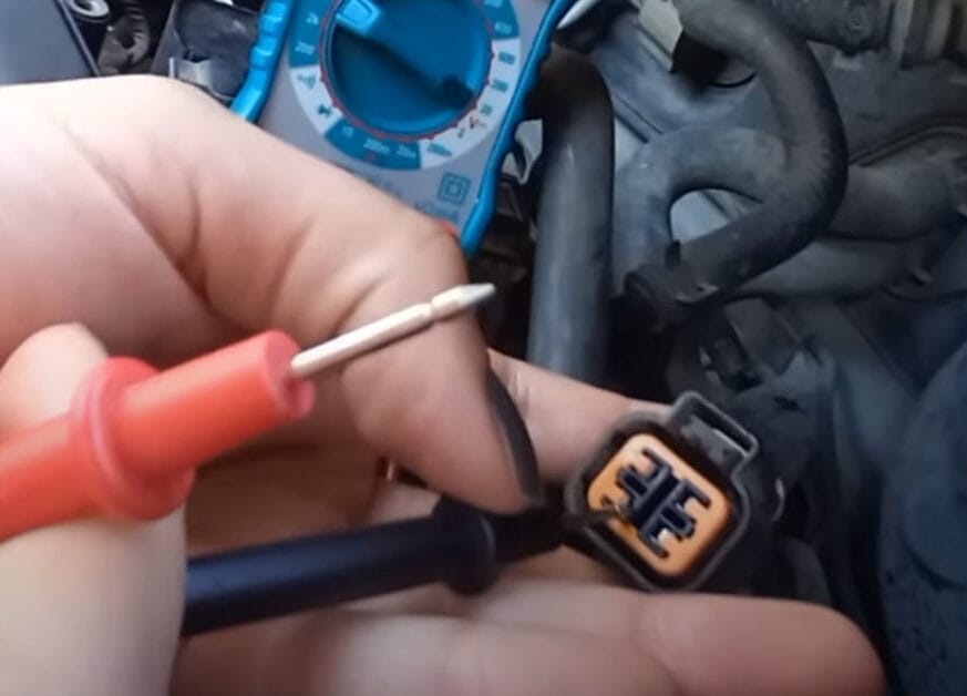 A person is holding the red and black probe of a multimeter