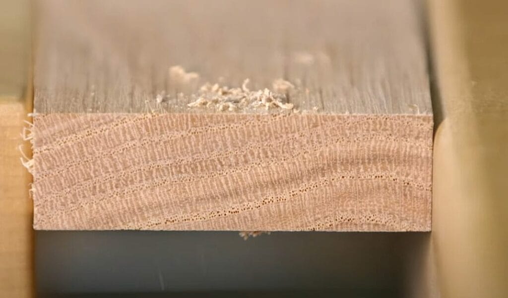 A close up of a piece of wood with a debris at the top of the hole area