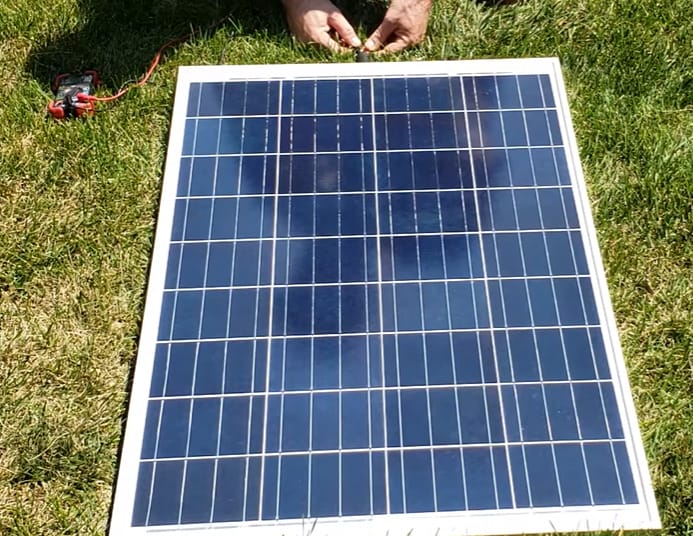 A person conducting solar panel testing on the grass