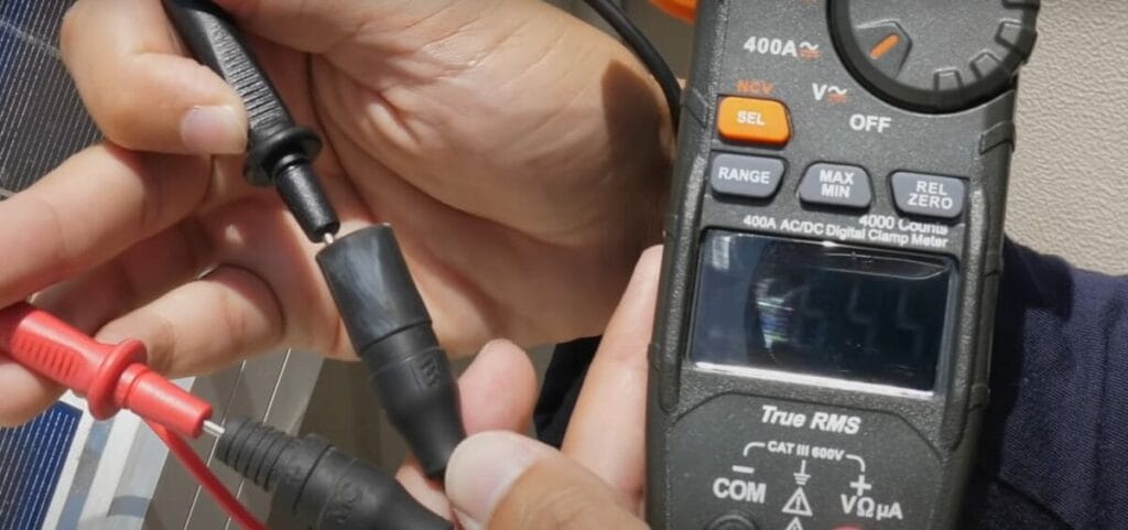 An individual performing solar panel testing using a multimeter