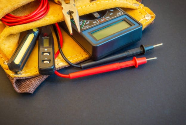 Electrician's tools in a leather bag on a black background