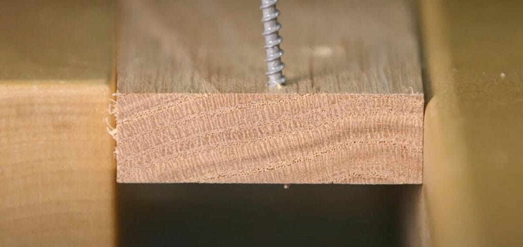 A close up of a wood piece with a drill bit to drill a hole in it