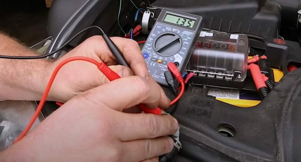 A man using a multimeter to check the battery in a car