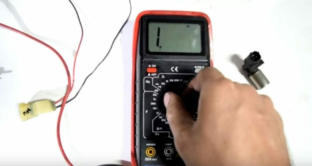 A person setting the multimeter to ohms